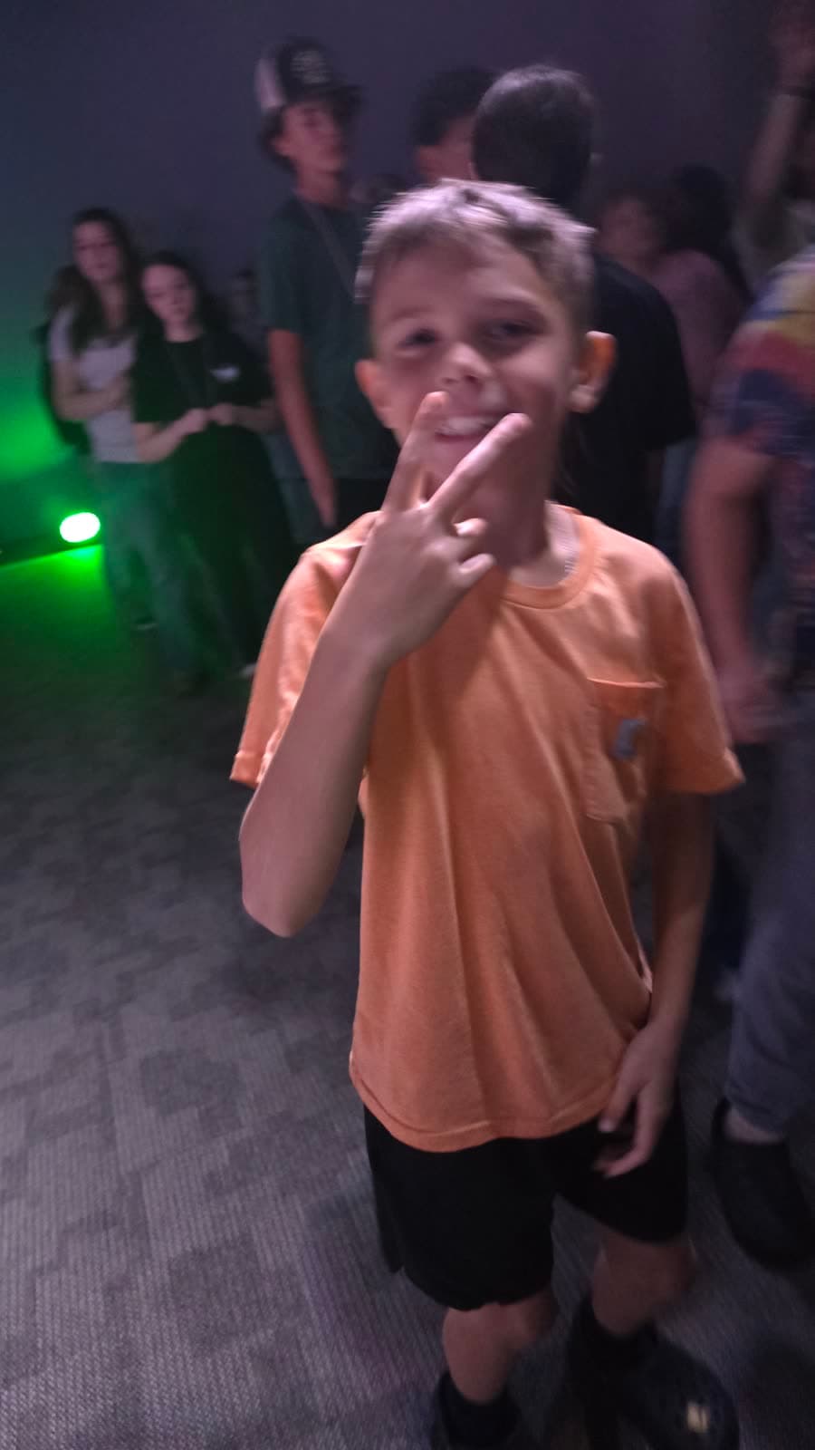 A boy grinning and flashing a peace sign at a CrossOver night