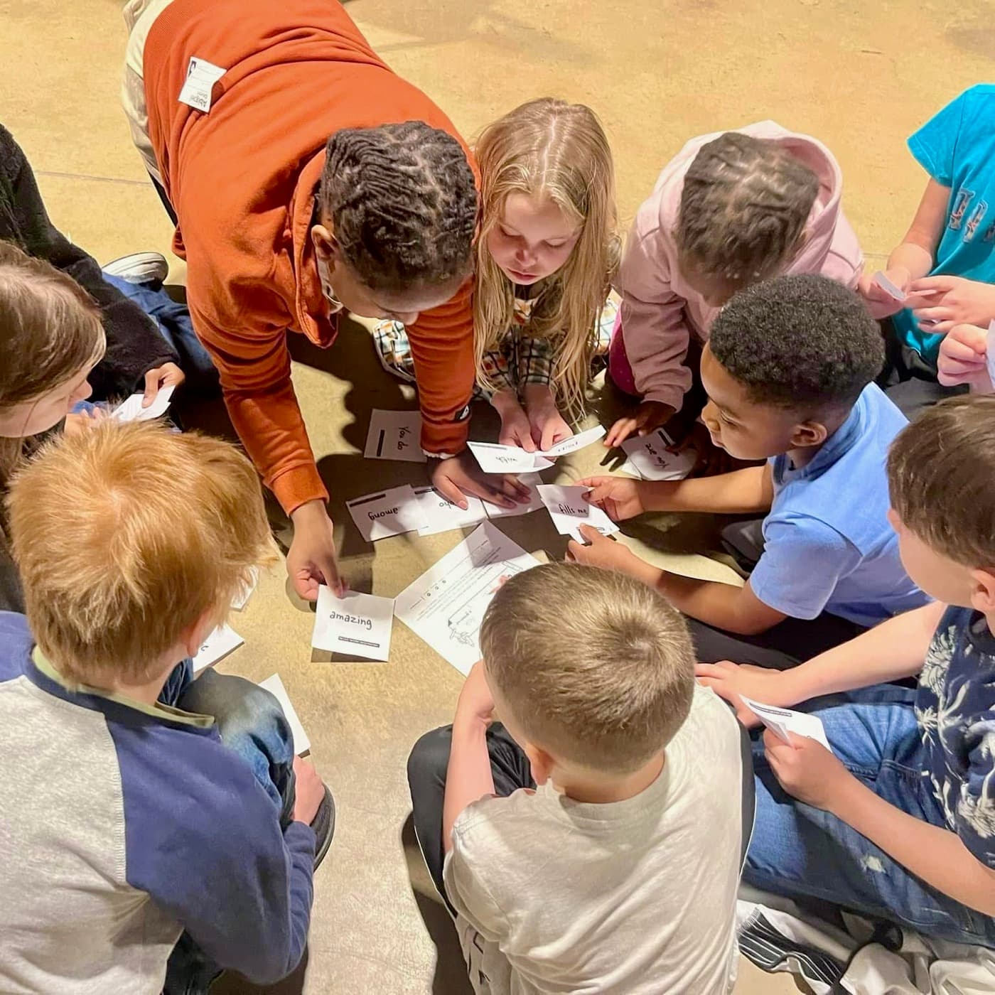 GCG Kids gathered in a circle on the floor, piecing a Bible verse together from cards