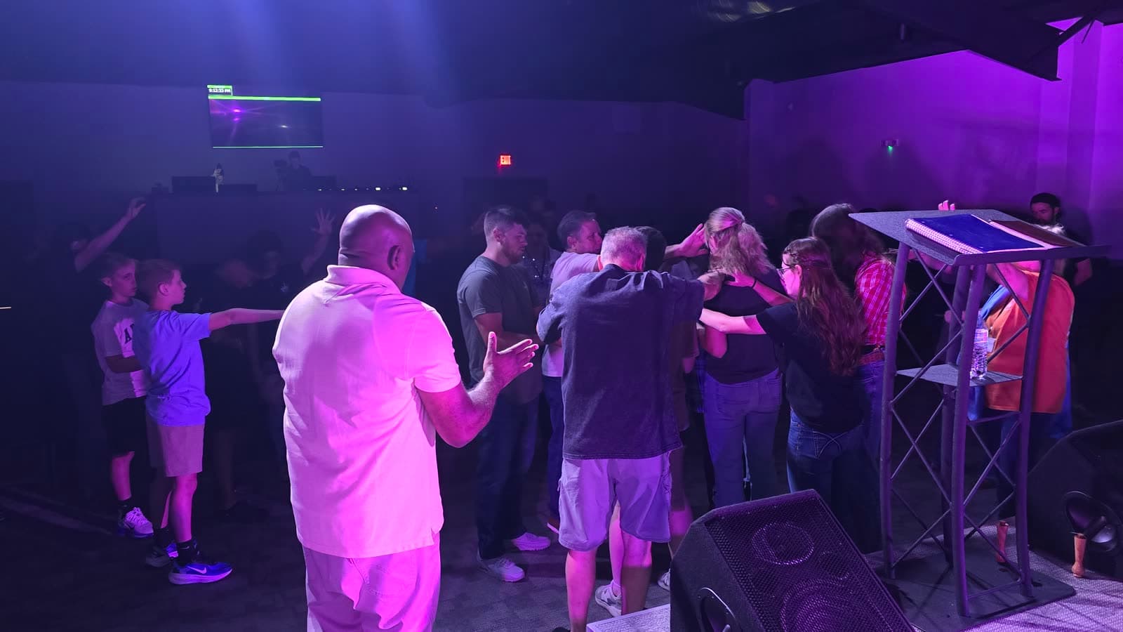 A circle of people at CrossOver praying with their hands on each other's shoulders