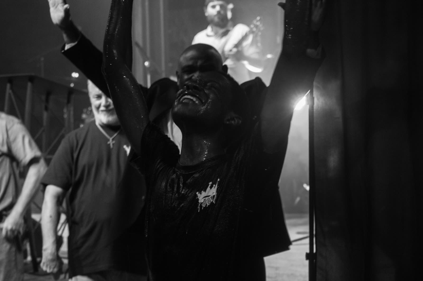 A young man coming up out of the water at a baptism, arms raised